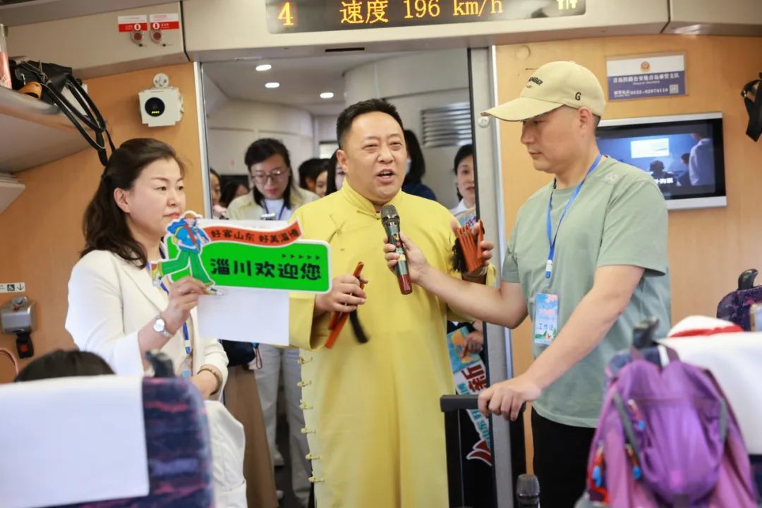 淄博非遗传承人在“烧烤专列”上向旅客展示山东快书。