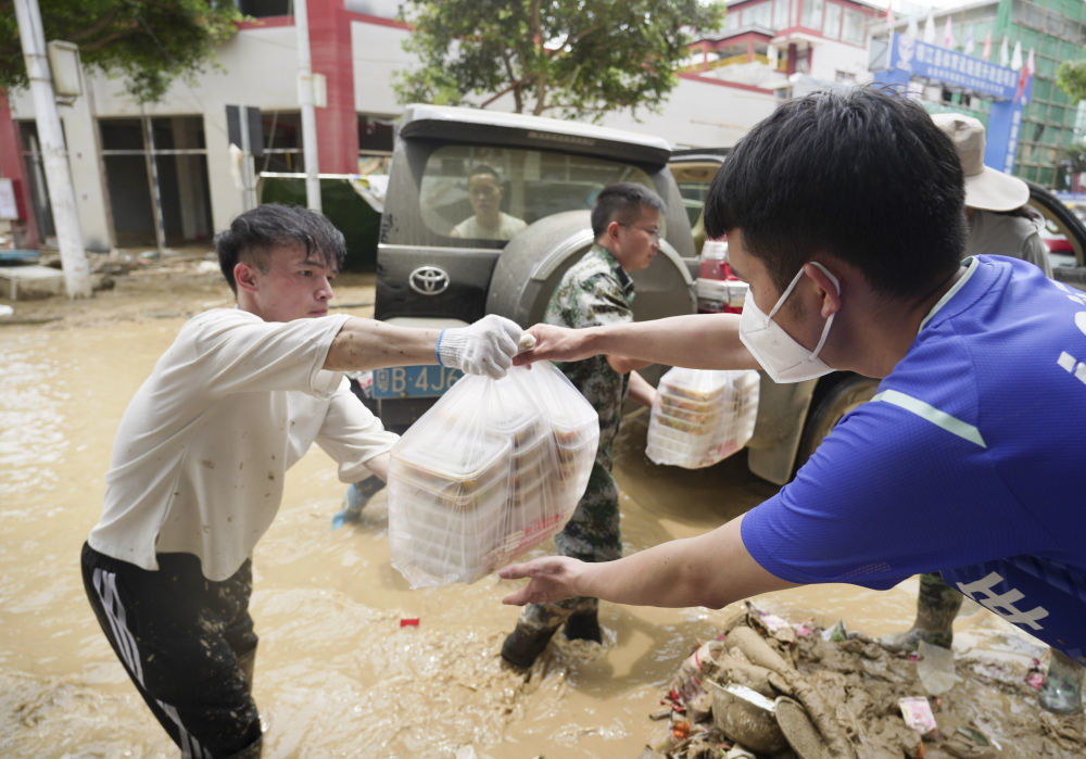 ↑6月26日,工作人员将盒饭送到救灾一线。