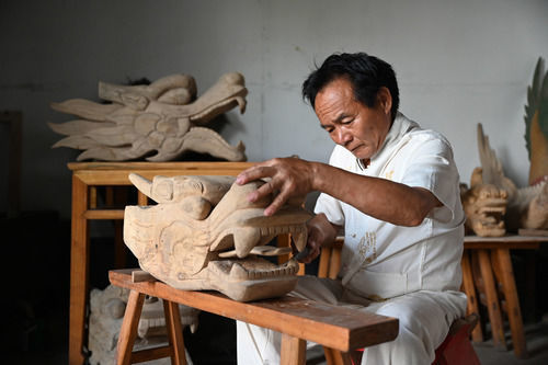 ↑湖南省汨罗市屈子祠镇九子龙屈原龙舟厂内，许桂生正在雕制龙头（2020年6月13日摄）。