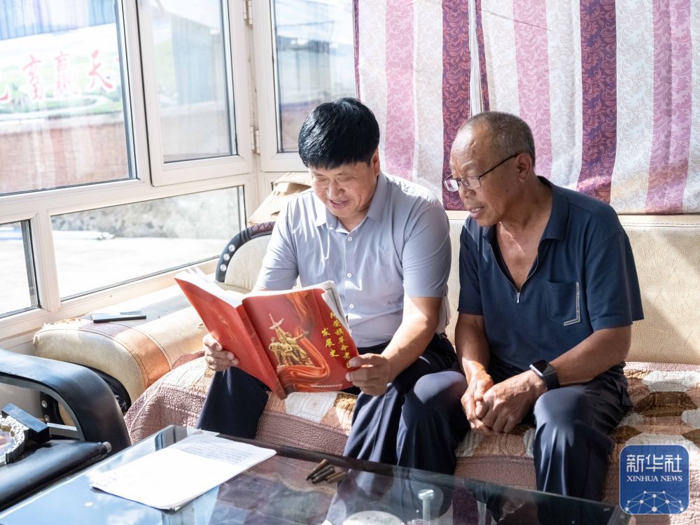 ↑8月23日,内蒙古呼伦贝尔市阿荣旗六合镇,孙福贵(左)在家中与村民李洪海一起查阅东北抗联在阿荣旗活动的历史资料。新华社记者 马金瑞 摄