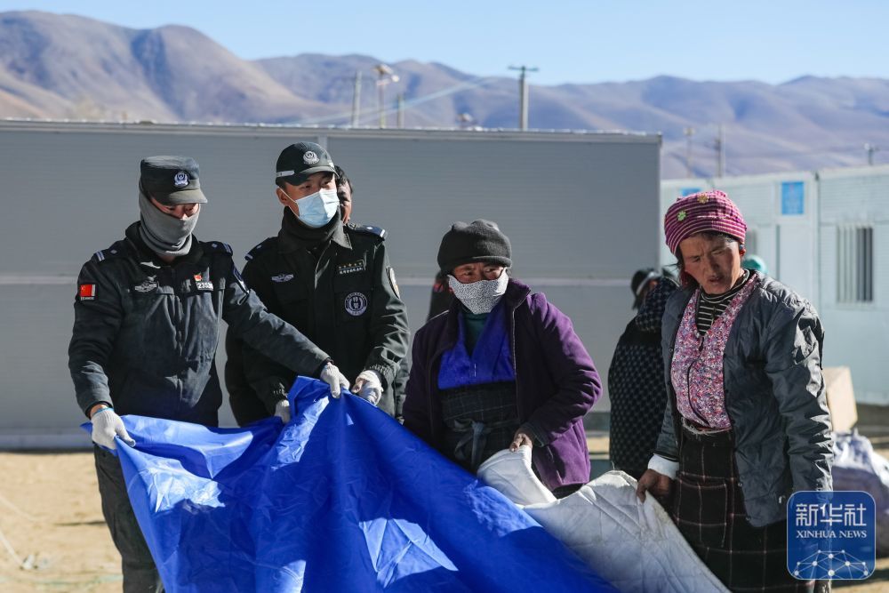 1月10日，在定日县长所乡古荣村，警察帮助搬入板房的受灾群众收帐篷。新华社记者 沈伯韩 摄