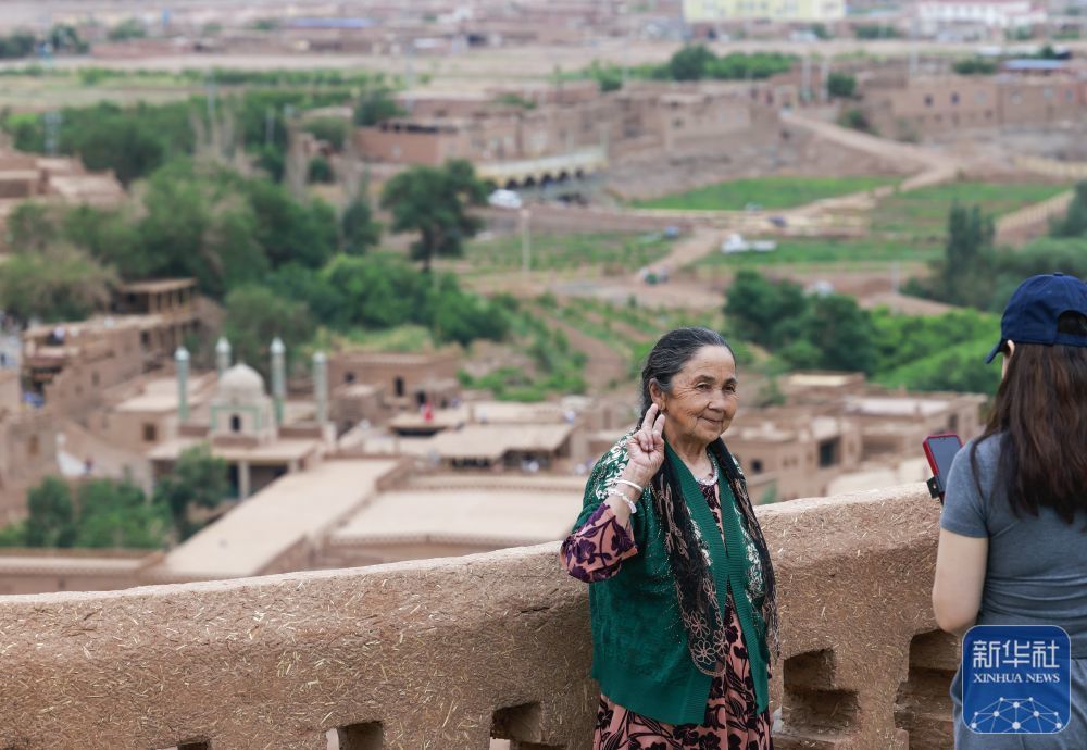 ↑ 5月4日,游客在新疆吐鲁番市鄯善县吐峪沟景区附近的观景平台拍照留影。