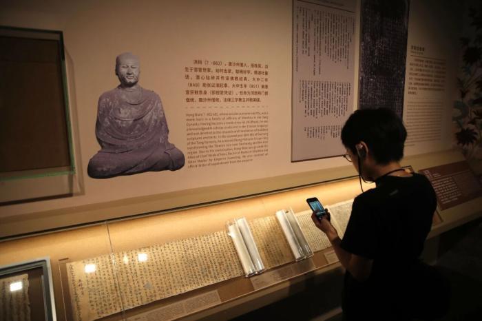 2024年9月20日，“何以敦煌”敦煌艺术大展在中华艺术宫（上海美术馆）拉开帷幕。图为观众参观敦煌藏经洞的部分文物书卷。中新社记者　张亨伟　摄