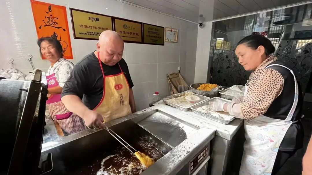 朱学贵(左二)在小吃店里炸洋芋粑粑。农民日报全媒体记者 刘学 摄