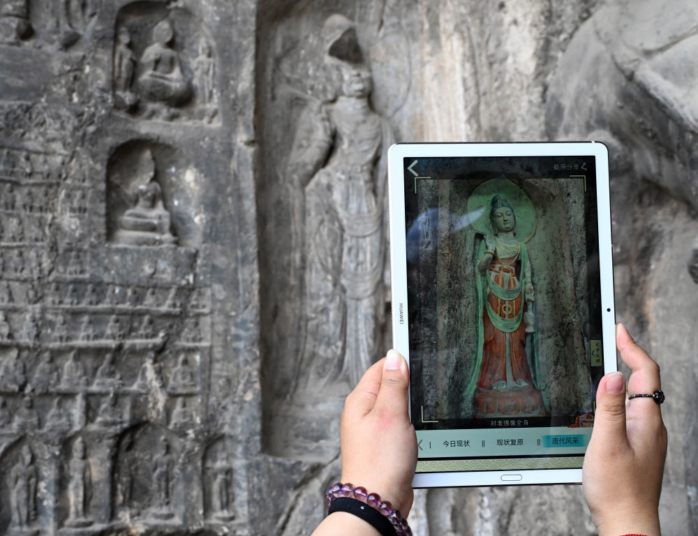 4月10日，龙门石窟研究院工作人员在万佛洞前查看数字化复原后的窟前南壁菩萨造像。