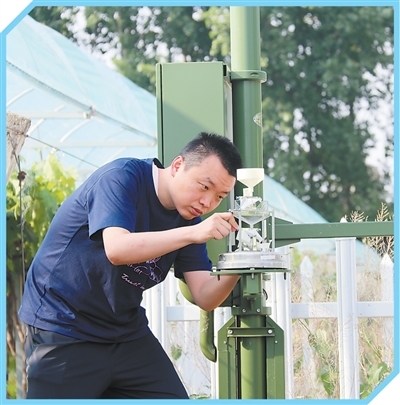 雷宇在位于成蹊家庭农场的气象观测站里清洁雨量筒。本报记者 高 炳摄