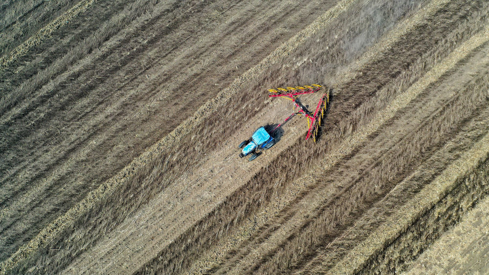 2024年4月2日，农民在吉林省公主岭市范家屯镇驾驶农机整理耕地里的秸秆（无人机照片）。