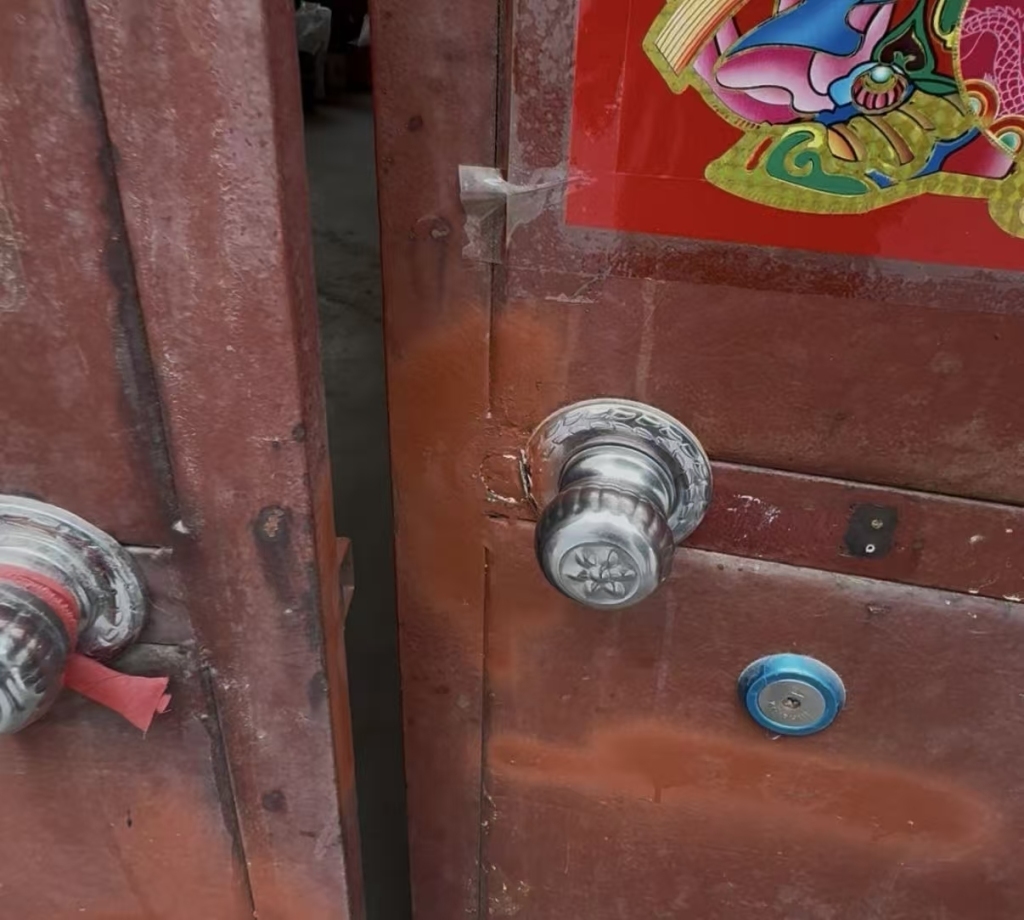 勘验笔录显示被破坏致“锁舌撕裂”的申红良家大门,如今已换了新锁,但大门修补痕迹明显。