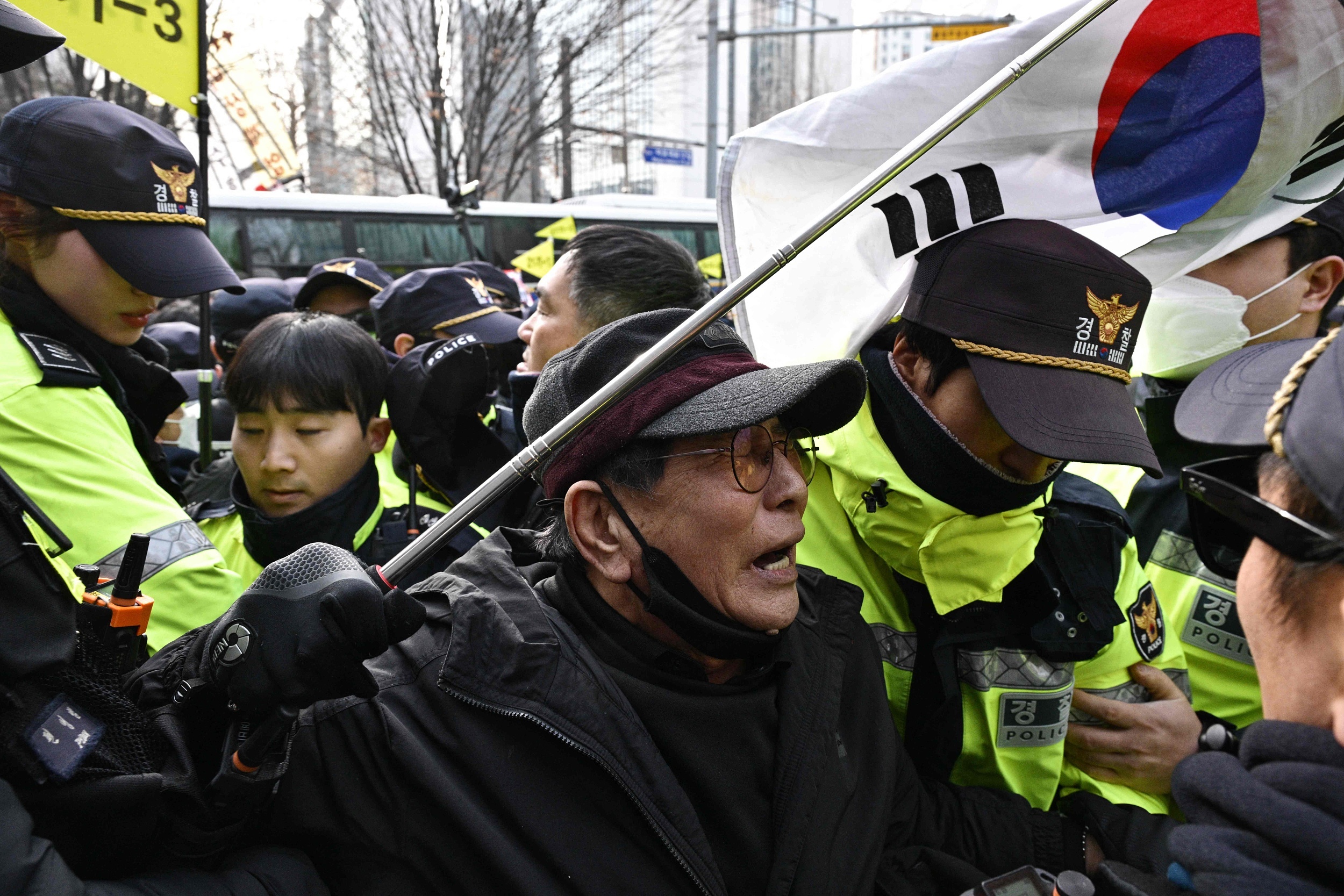 当地时间2025年1月18日，韩国首尔，在首尔西部地方法院外，随着抗议者与警方之间发生冲突，一名总统尹锡悦的支持者情绪激动。视觉中国 图