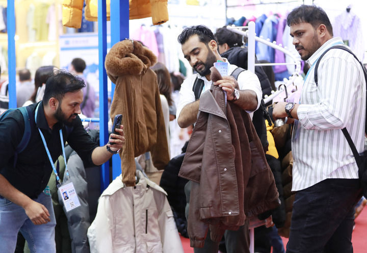 2025年5月1日，在广州开幕的第137届广交会第三期上，境外采购商在一家服装企业的展区拍摄样品。新华社记者 王瑞平 摄