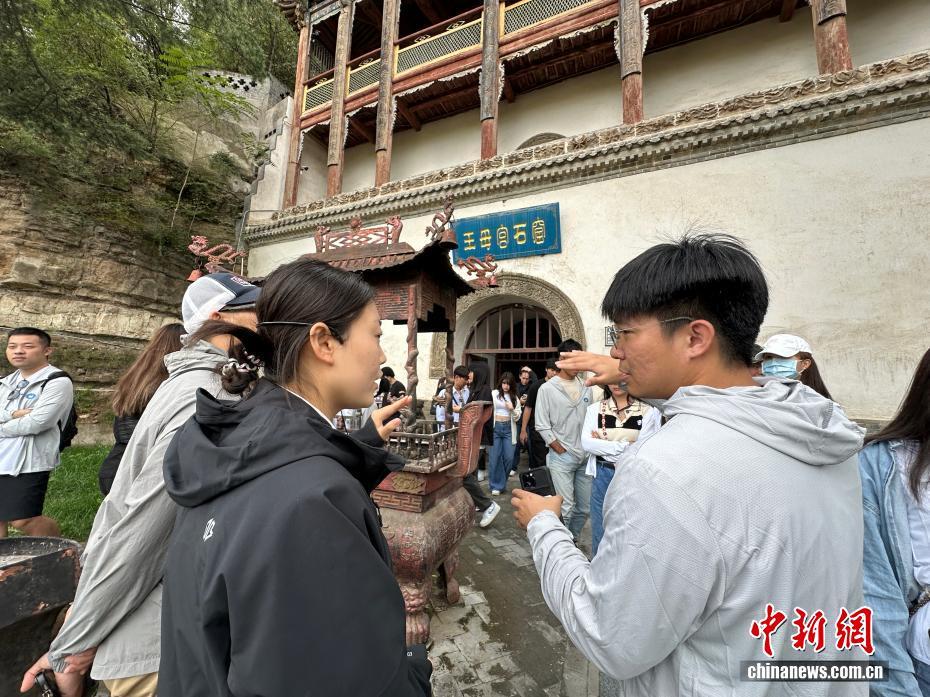 图为台青向讲解员询问王母宫石窟如何保护与传承 王牧雨 摄