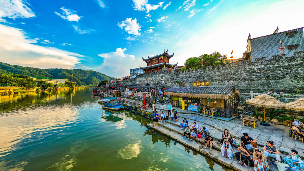 游客在福建龙岩长汀惠吉门前的汀江水畔休闲娱乐。朱芳彬摄