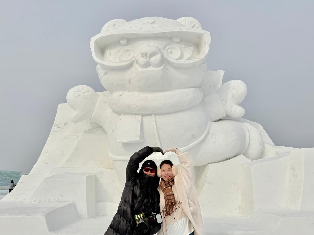 两名游客在哈尔滨冰雪大世界内的亚冬会吉祥物雪雕前拍照。新华社记者 杨思琪 摄
