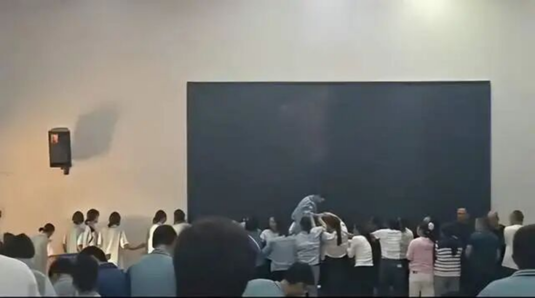 學(xué)生們疑似被蒙上眼睛、在老師和同學(xué)攙扶下從家長背上經(jīng)過