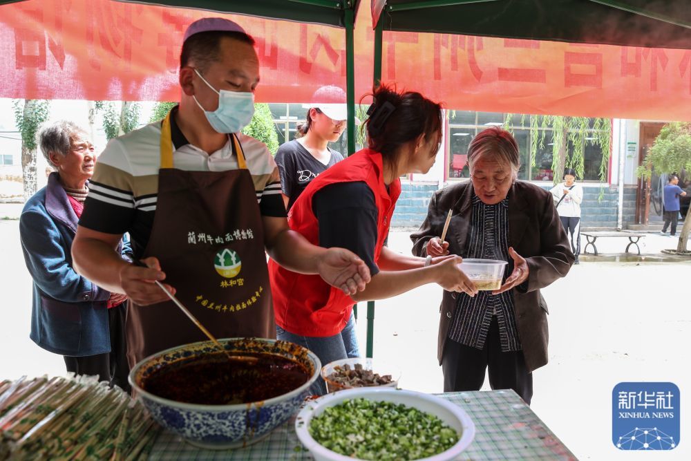↑ 8月9日，在榆中县第三中学安置点，爱心牛肉面企业工作人员和志愿者为受灾群众盛牛肉面。
