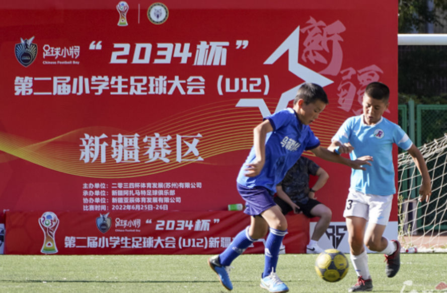 “2034杯”第二届小学生足球大会（U12）新疆赛区比赛中，乌鲁木齐市第121小学足球队员（左）在和对手拼抢。杨伟 摄