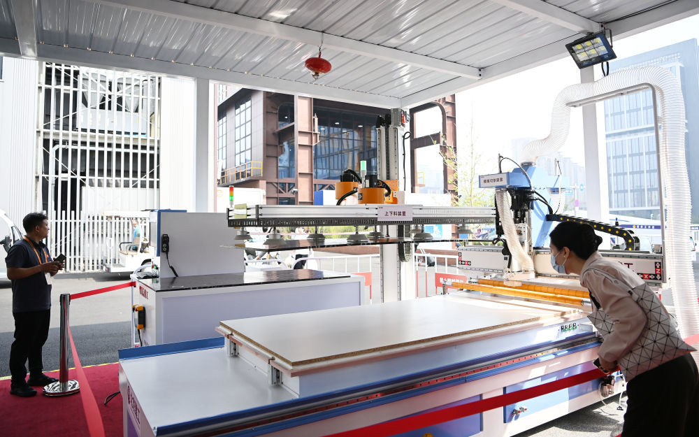 ↑ 9月11日，在服贸会工程咨询与建筑服务专题展区，参观者（右）在北京建工展台参观智能模板无人工厂。