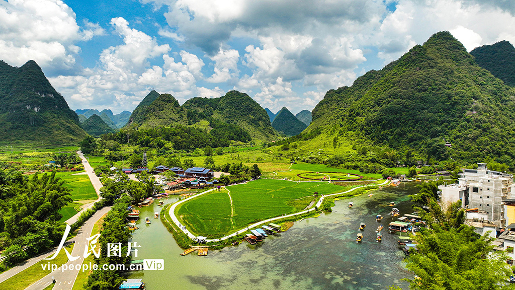 在广西壮族自治区靖西市新靖镇鹅泉村，游客乘坐竹排泛舟湖上，欣赏山水美景 图源：人民图片