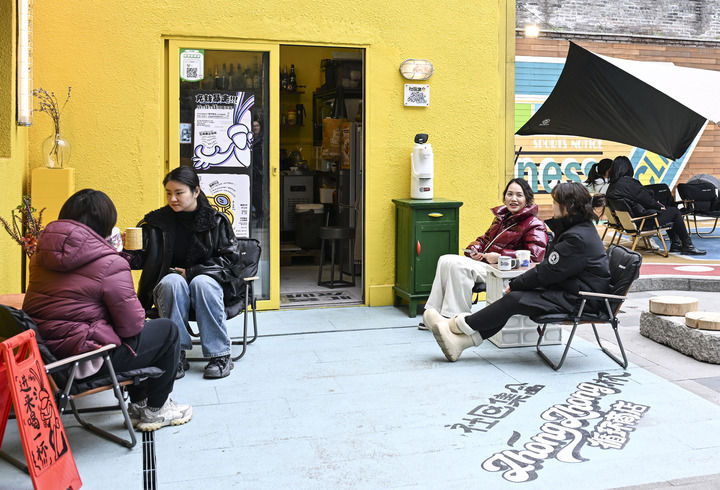 消费者在重庆市江北区大石坝街道忠恕沱社区一饮品店外休闲、聊天（2月24日摄）。新华社记者王全超摄
