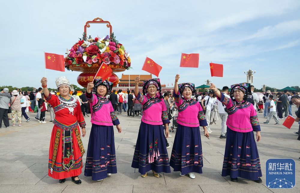 ↑ 10月1日,来自贵州的布依族游客在北京天安门广场游览拍照。新华社发(梁志强摄)