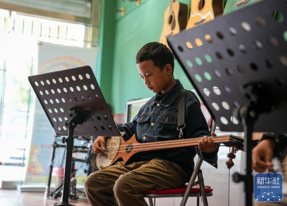 ↑ 9月13日，在拉萨市古乐扎念琴行，一名男孩在弹奏扎念琴。