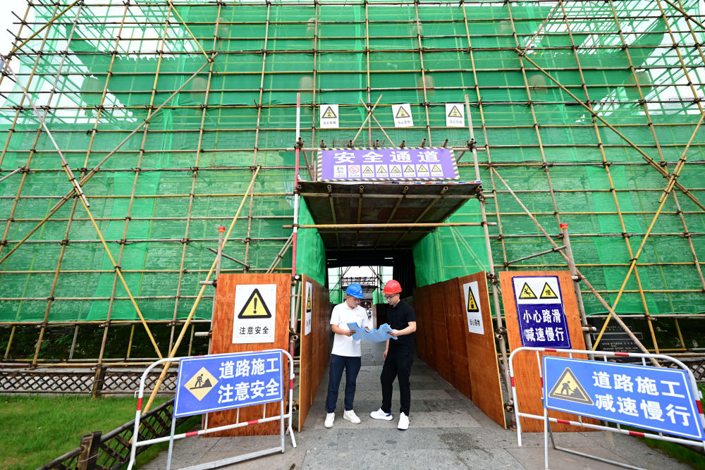 6月19日,周虎(右)在歙县徽州古城南谯楼保养维护工程现场查看。