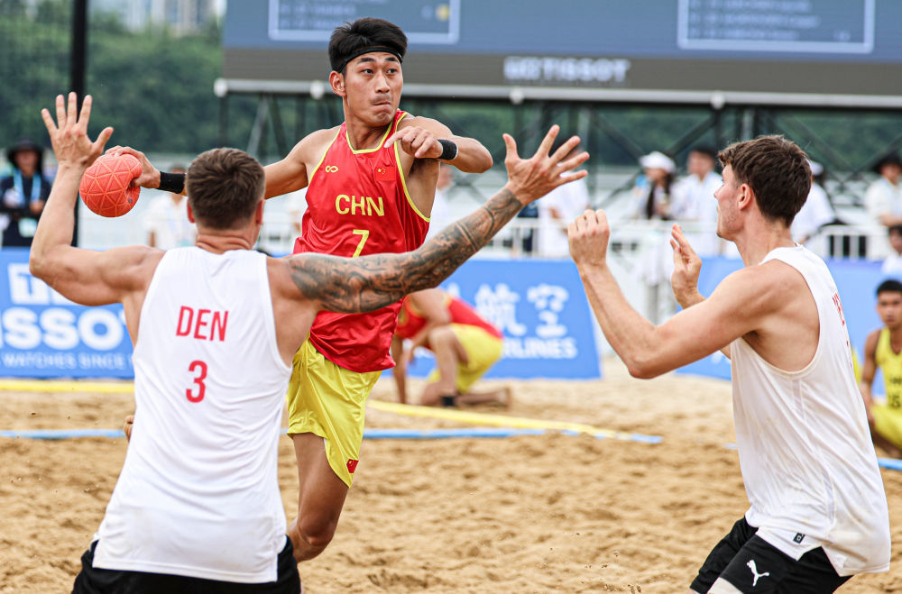 8月11日,中国队球员任健豪(上)在比赛中进攻。当日,在2025年成都世运会沙滩手球男子第5-8名安慰赛半决赛中,中国队0比2不敌丹麦队。新华社记者 刘坤 摄