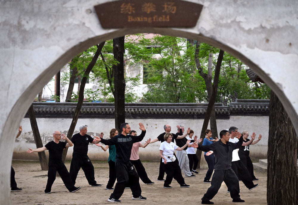 2024年4月18日,陈少拳(前左)和师父陈自强(前右)以及来自法国的学员们在陈家沟杨露禅学拳处练习太极拳。