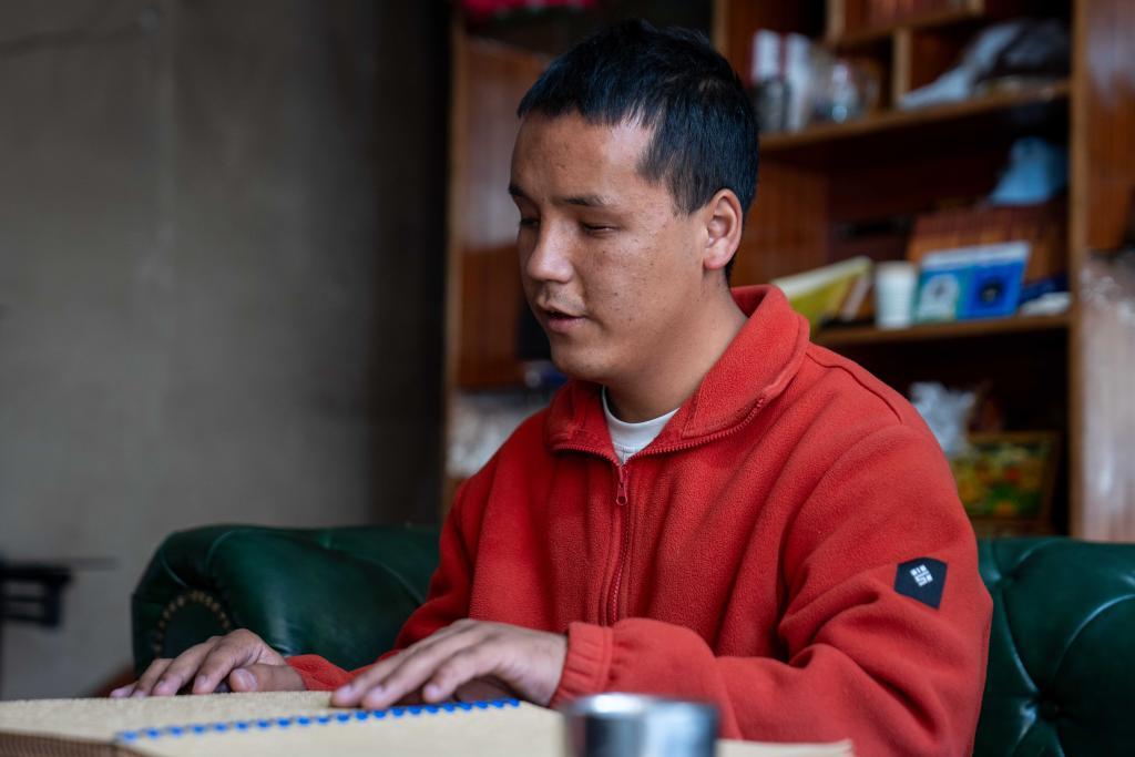 2025年10月10日，达瓦次仁在“阅读”盲文书籍。