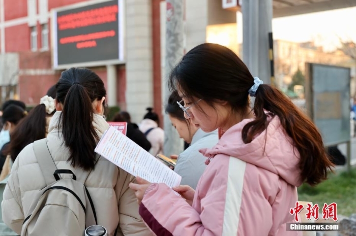 资料图:2024年12月1日,北京首都师范大学附属丽泽中学初中部考点外,考生抓紧时间复习。中新社记者 易海菲 摄