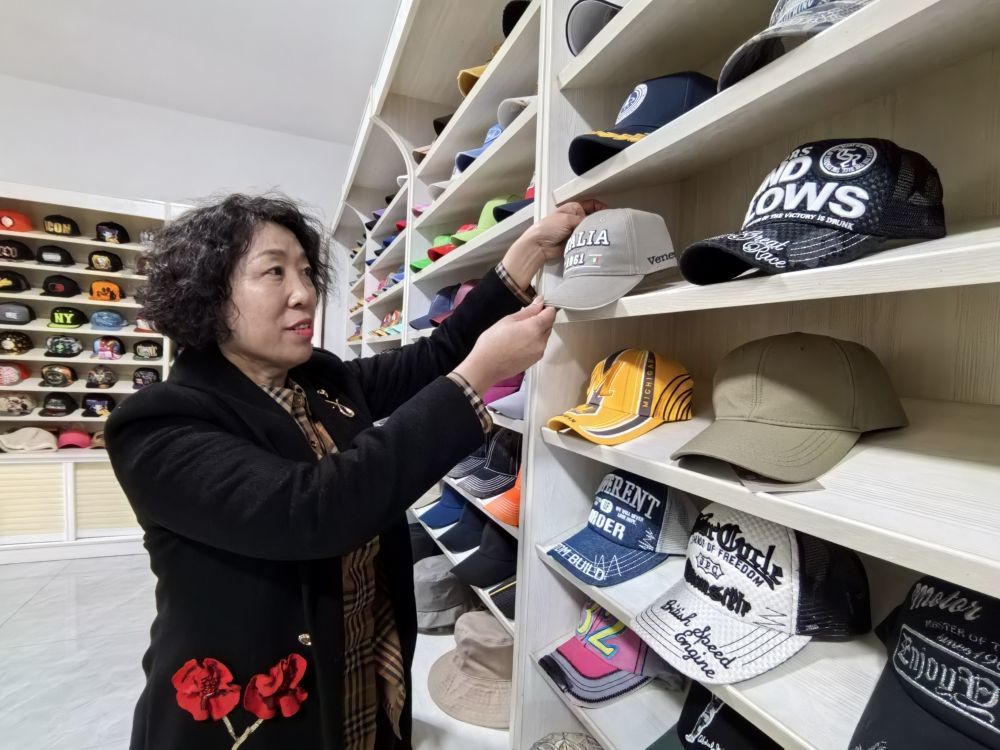 青岛金丰盛泽帽业有限公司的展厅里，工作人员在介绍运动帽的品类。新华社记者 王欢 摄