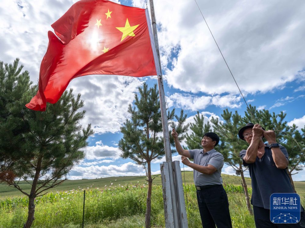 ↑8月23日,内蒙古呼伦贝尔市阿荣旗六合镇,孙福贵(左)与村民李洪海在“红军岗”上升旗。新华社记者 马金瑞 摄