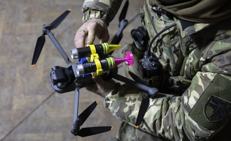 一名乌军士兵给改装后的大疆Mavic 3型无人机安装手榴弹。大疆公司于2022年宣布暂停在俄罗斯和乌克兰的业务，但双方仍能从第三方购买。 外媒