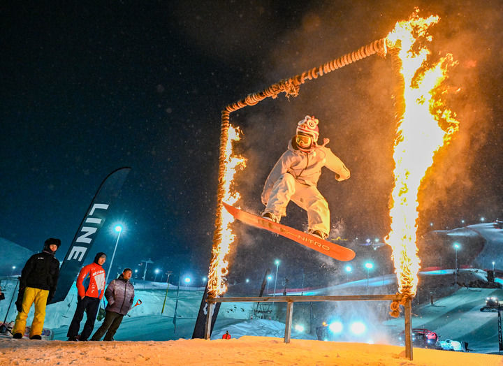 在坐落于阿勒泰市城区的新疆将军山国际滑雪度假区，雪友在新春趣味滑雪公园跳台活动中钻过火圈（2025年1月29日摄）。新华社记者 陈朔 摄