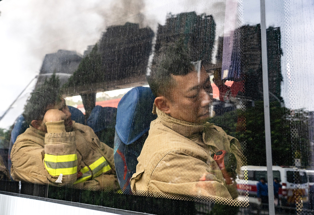 11月27日上午,消防人员持续在香港大埔宏福苑火灾现场进行救援,轮替的消防员短暂休息。