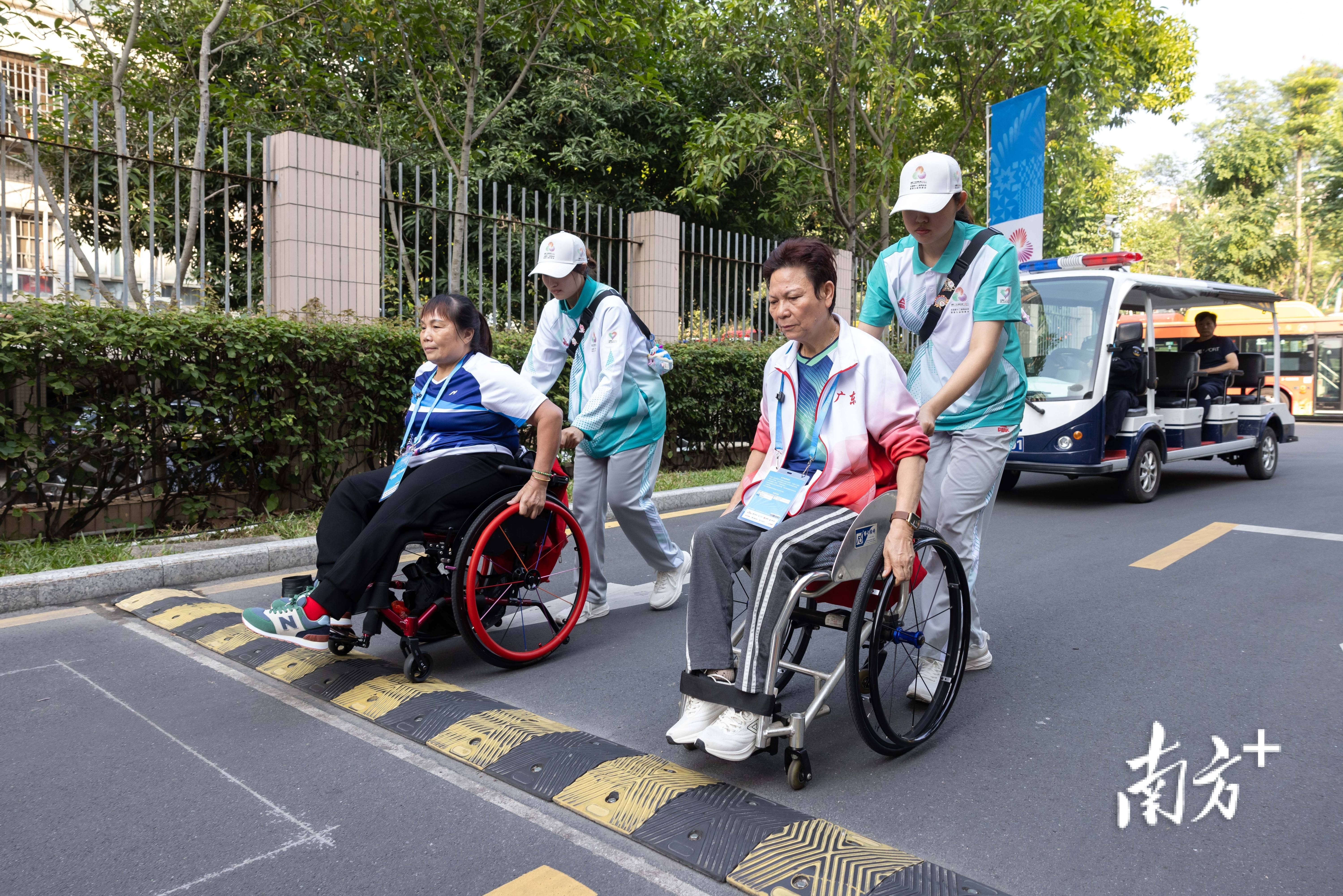 黄丽明(右)与自己的双打搭档吴桂妹在志愿者的协助下前往训练馆练球。