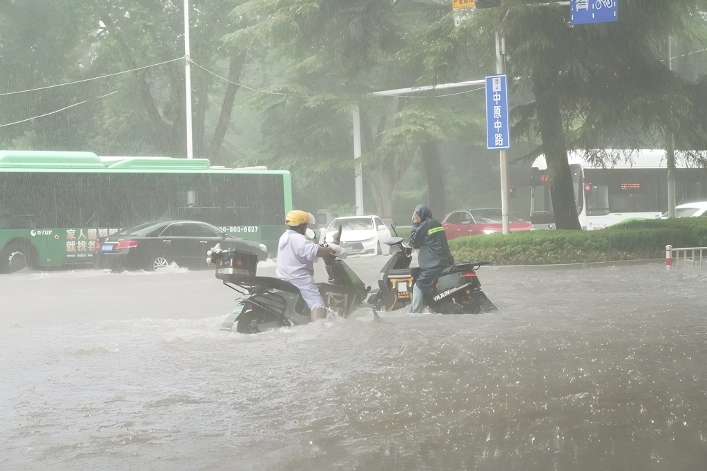 2025年8月7日，河南郑州，市民骑行通过中原区积水路段。 中新社记者 李超庆/视觉中国 图