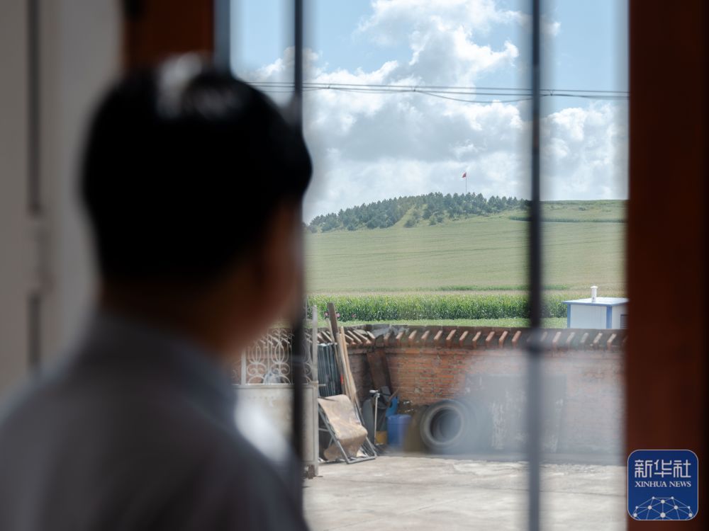 ↑8月23日,内蒙古呼伦贝尔市阿荣旗六合镇,孙福贵在家中透过窗户遥望“红军岗”。新华社记者 马金瑞 摄