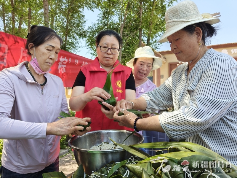 5月31日,博乐市贝林哈日莫墩乡玛尼乡村的志愿者和村民一起包粽子。田朝阳 摄