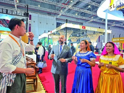 第八届进博会老挝展厅,工作人员邀请萨尔瓦多游客品茶。本报记者 范天培摄/光明图片