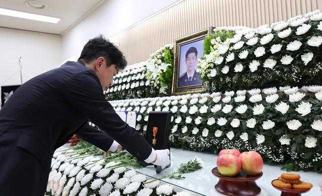 韩国总统秘书室长姜勋植在牺牲海警灵前摆放勋章 图源:韩联社