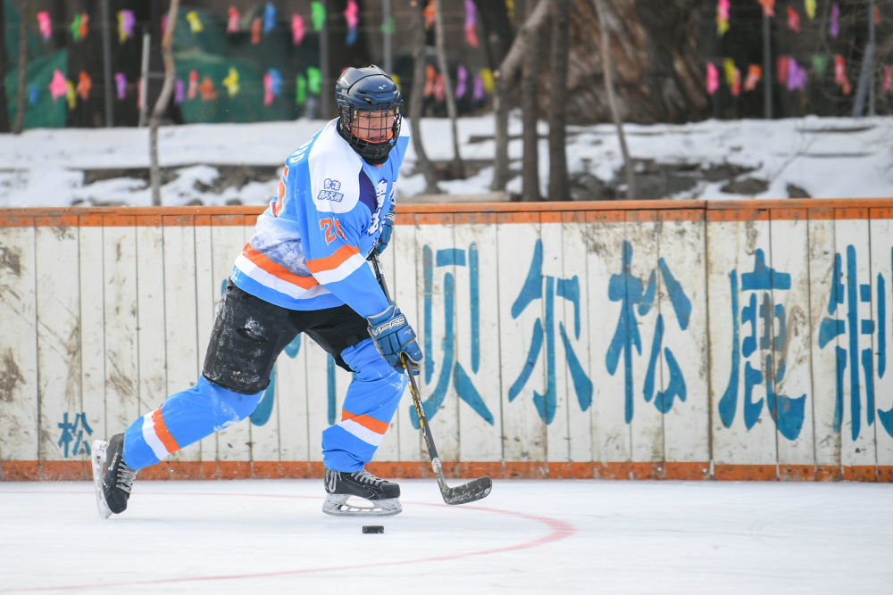 ↑2022年1月9日，在内蒙古扎兰屯市吊桥公园内，一名冰球爱好者在打冰球。