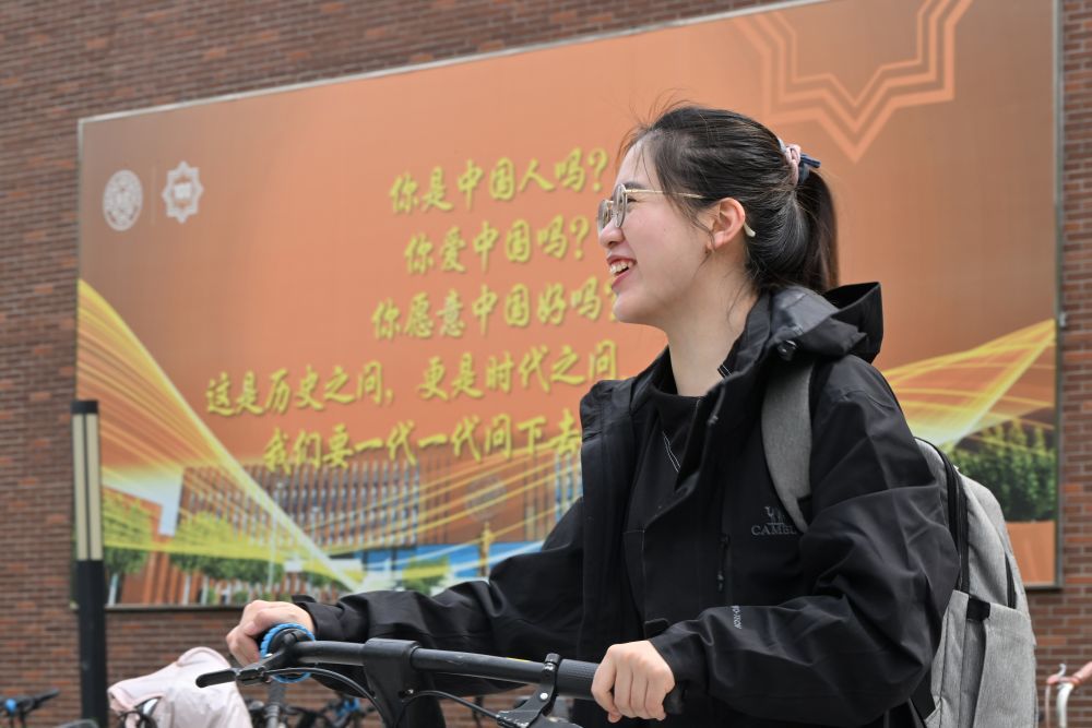 5月8日，杨雅丽在南开大学津南校区一面写有“爱国三问”的墙前留影。