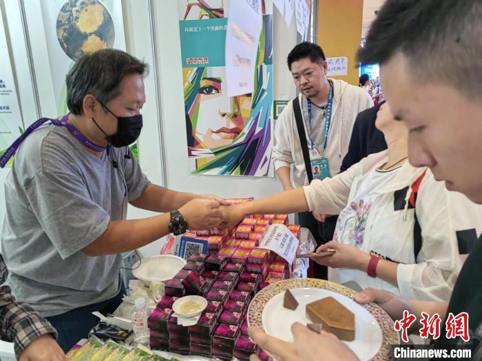 图为泰国商人在南博会上向顾客推荐草药香皂。王胜嫔 摄