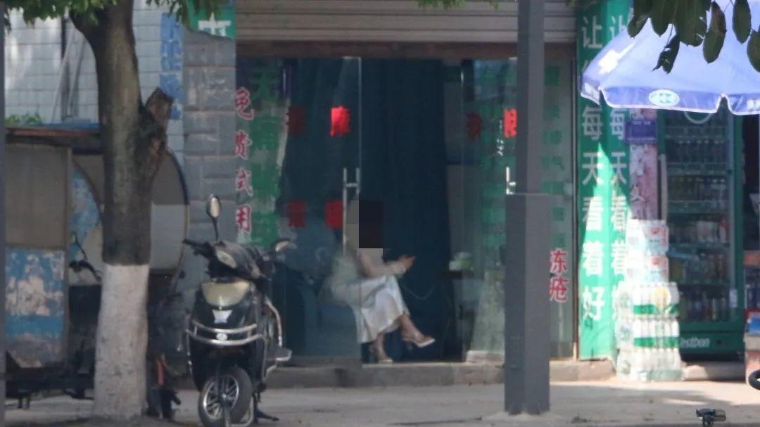 ▲按摩店女店员坐在门口招揽“生意”