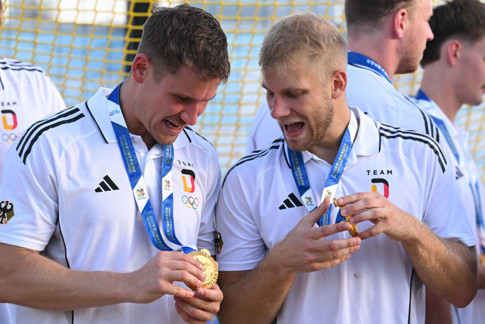 ↑8月12日,冠军德国队球员在成都世运会男子沙滩手球颁奖仪式上查看奖牌。