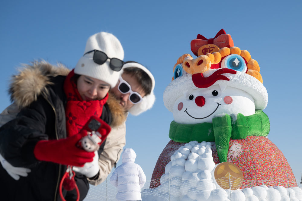 ↑1月4日，在北大荒集团闫家岗农场，游客与雪人合影。新华社记者 张涛 摄