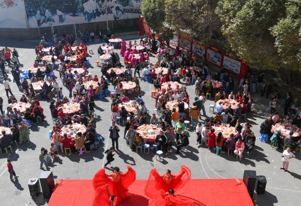 人们在乌鲁木齐市天山区固原巷社区举办的活动中品尝百家宴,欣赏文艺演出。新华社记者 王菲 摄