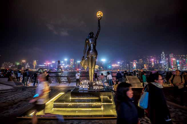 2019年12月15日,中国香港。周日夜间,人们走过尖沙咀星光大道,香港电影金像奖女神铜像矗立于此。(图/CFP)