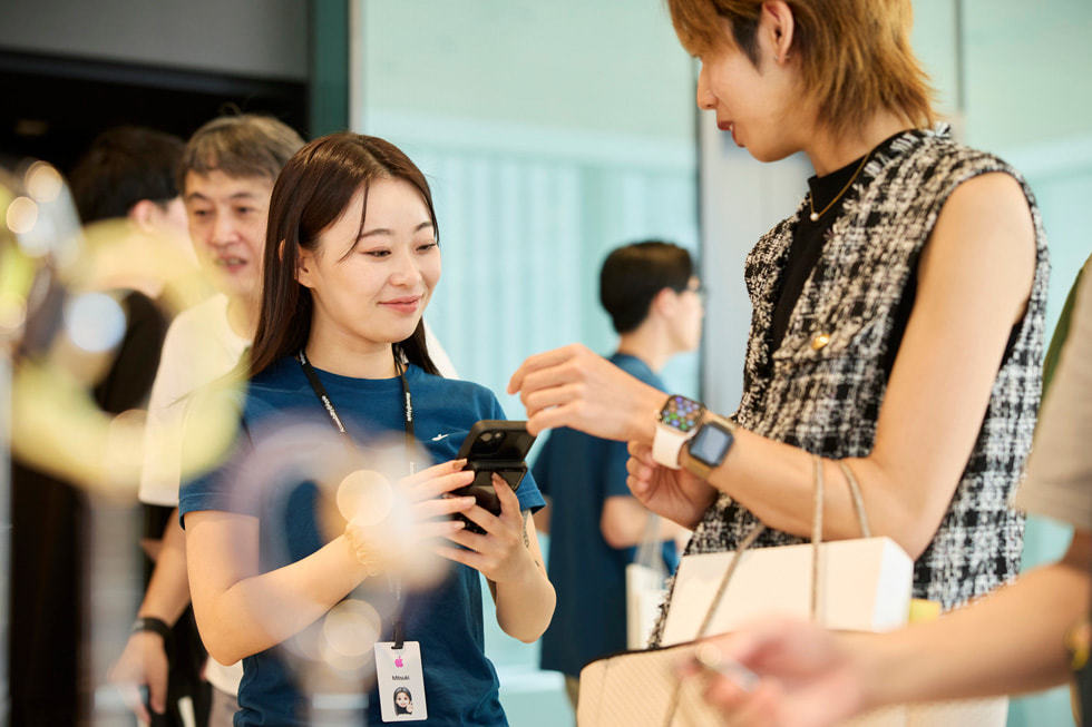 Apple 银座零售店内，一名团队成员在帮助一位顾客试戴 Apple Watch。